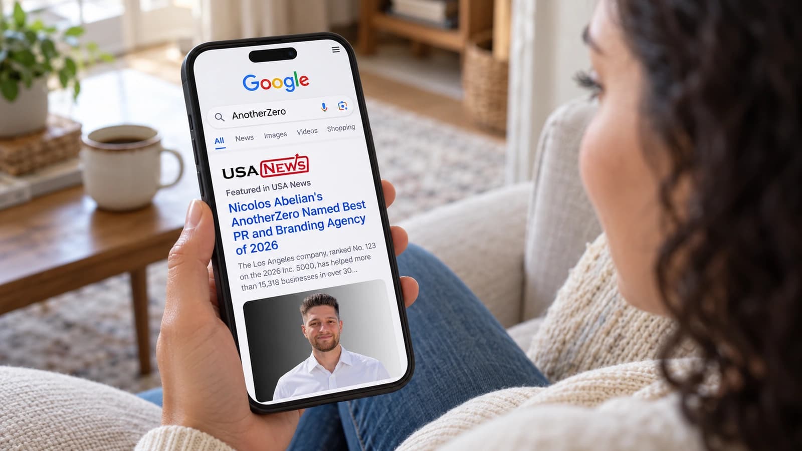 A woman at home sees an AnotherZero feature in USA News while searching on her phone.