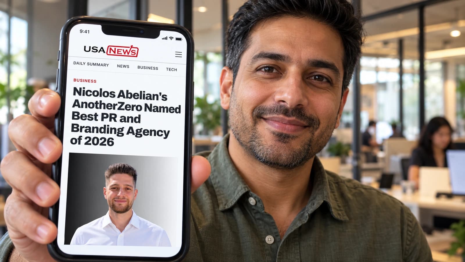 A business owner shows a phone with the AnotherZero USA News feature in his office.