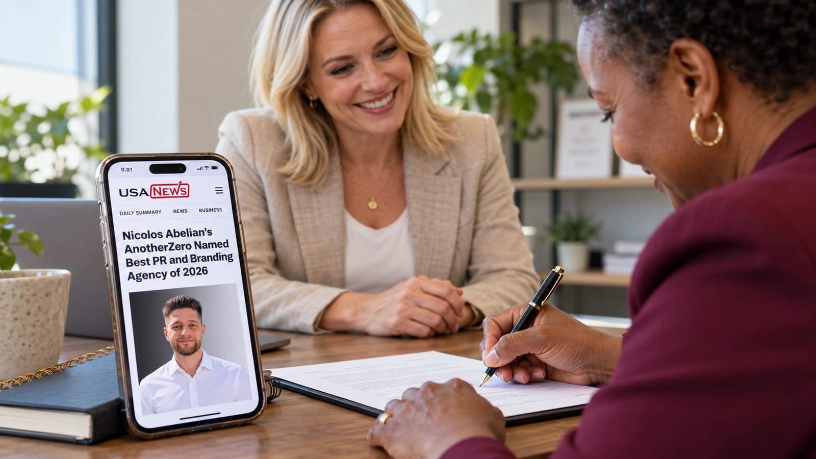 A client signs an agreement beside a phone showing the AnotherZero USA News feature.